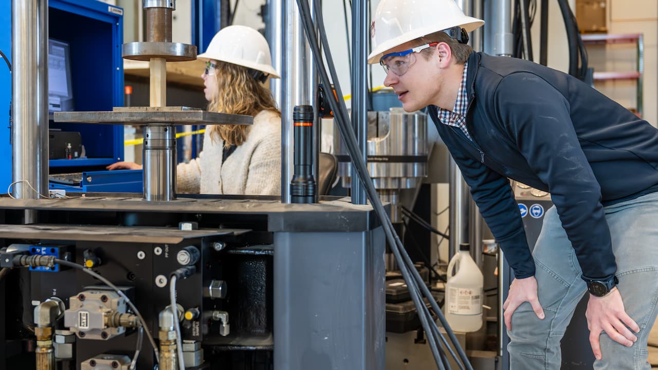two students testing a wood sample in an engineering lab